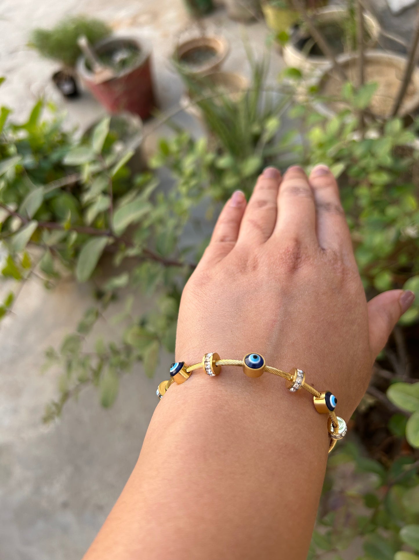 A gold-plated bracelet with blue and white elements displayed on a person's wrist.