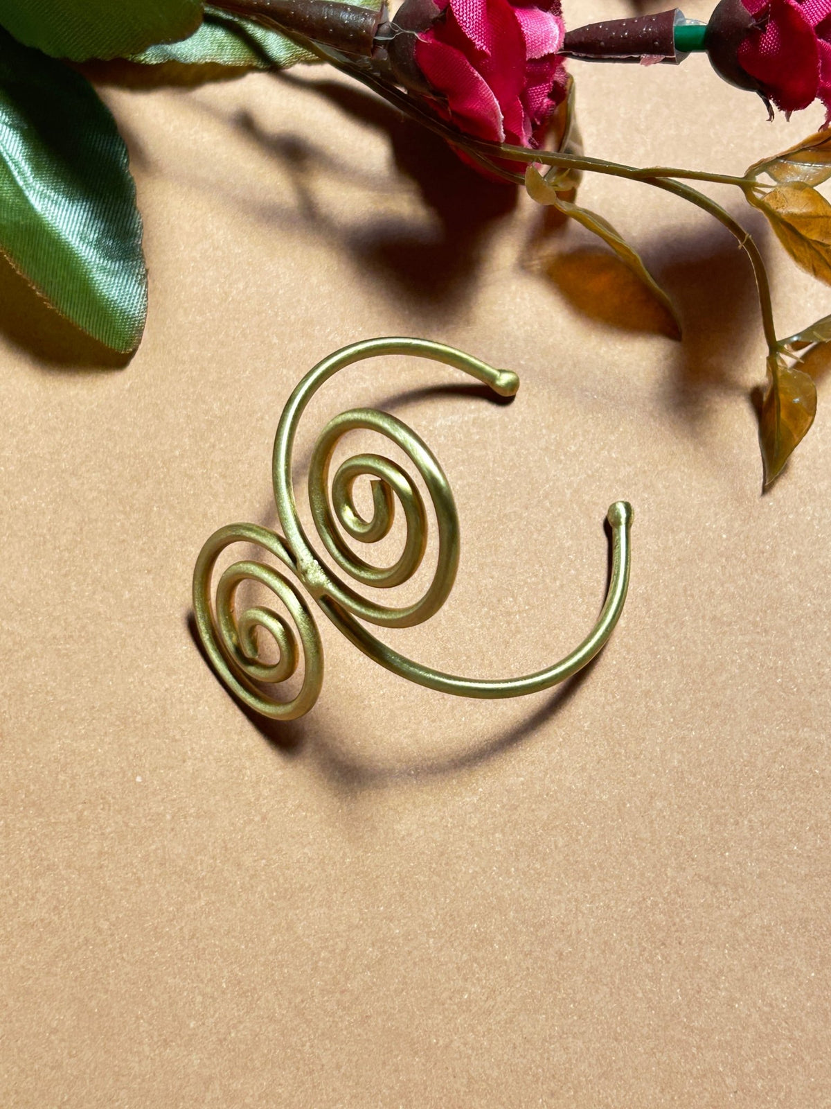 Flat lay of Handcrafted Spiral Swirl Brass Bracelet - CharmsCrafted